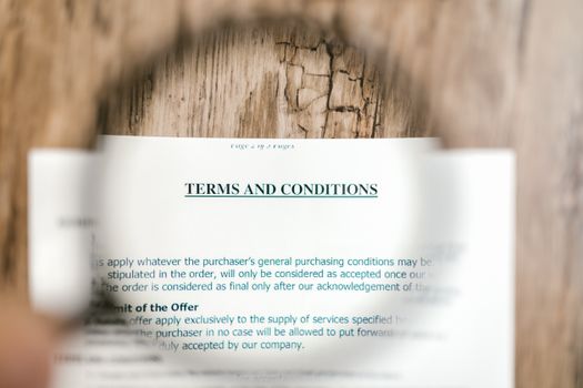 Magnifying glass focusing on terms and conditions document